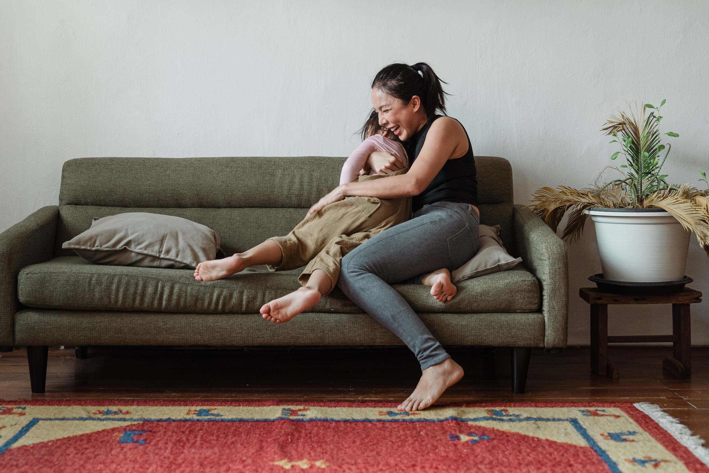 Photo of Woman Sitting on Couch While Hugging Her Child